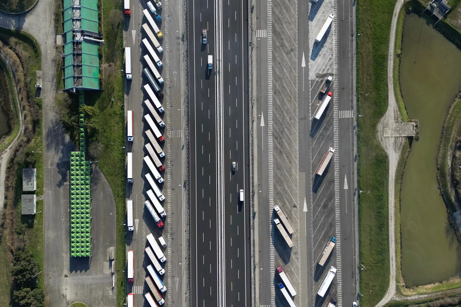Vrachtwagens langs een snelweg, recht van boven gefotografeerd.